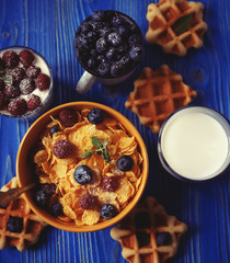 Healthy breakfast. Corn flakes with raspberries and blueberries, granola with yogurt and berries, wafers and milk.