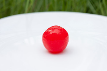Sugar coated red cherries are used to decorate desserts in white plate.