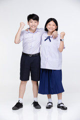 Aasian girl and boy in student's uniform on gray background.