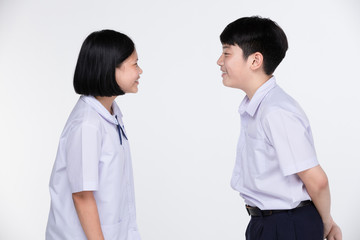 Aasian girl and boy in student's uniform on gray background.