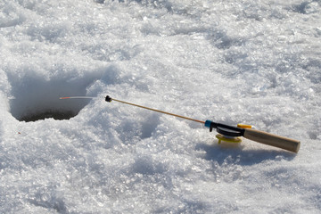 Winter fishing rod in the snow near the hole in the ice.