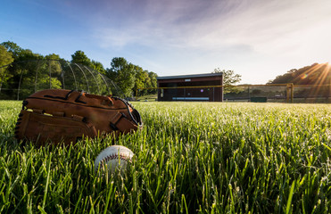 Baseball and glove in morning dew green grass