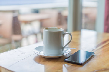 wooden table with cell phone, mobile phone and a mug of coffee in a relaxing break time scene 