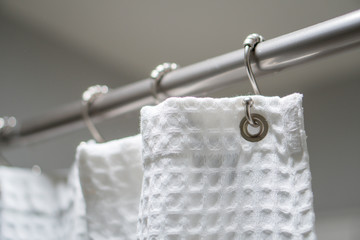 Decorative luxurious shower curtain on hooks.