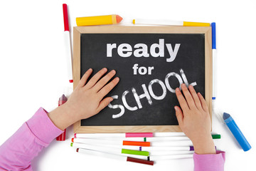 Getting ready for school concept depicted with child hands on blackboard with text - top view