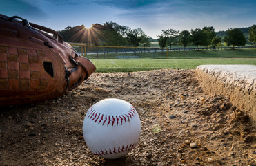 aseball and glove on pitchers mound on early morning springtime