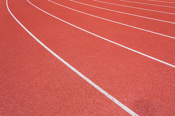 Fototapeta premium White lines of stadium and texture of running racetrack red rubber racetracks in outdoor stadium are 8 track and green grass field,empty athletics stadium with track.
