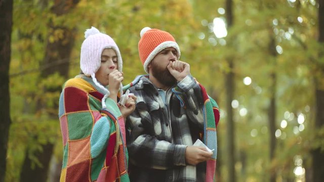 Young couple with handkerchief. Nose wiper near autumn tree. Napkin sneezing in the autumn yellow park.