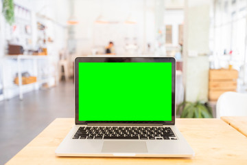 Fototapeta premium Mockup image of laptop with blank Green screen on wooden table of In the coffee shop.
