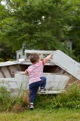 Toddler boy playing on wooden structure during summer - from behind   