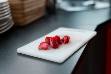 Strawberries cut into pieces on a white cutting board