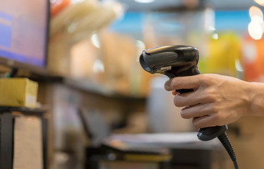 Close up barcode scanner in hand on blurred background,Inspection of goods in the warehouse,The concept of selling products in a supermarket,Spot focus,Copy space.