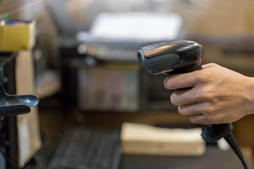 Close up barcode scanner in hand on blurred background,Inspection of goods in the warehouse,The concept of selling products in a supermarket,Spot focus,Copy space.