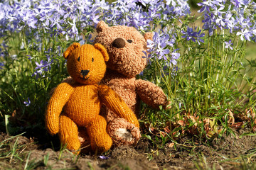 Little teddy bear sits back in the summer garden