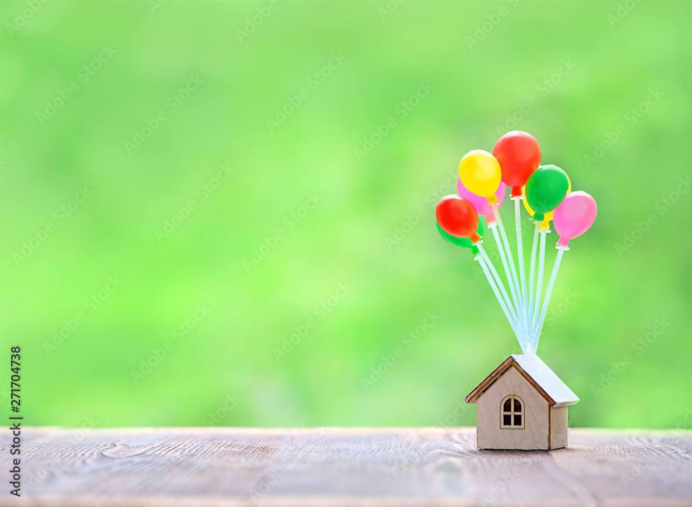 Wall mural air balloons and house on green nature background. home model hanging on colorful balloons. plan rea