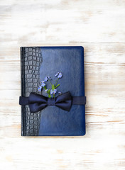 blue leather bound journal, flowers and bow tie. happy father's day concept, idea for gift dad, men, brutal style. holiday background. top view