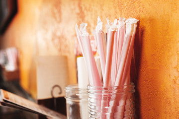 A jar of straws against a wall in a restaurant environment