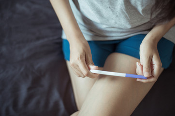 Obraz na płótnie Canvas Woman hand holding pregnancy test after testing in her bedroom,Close up