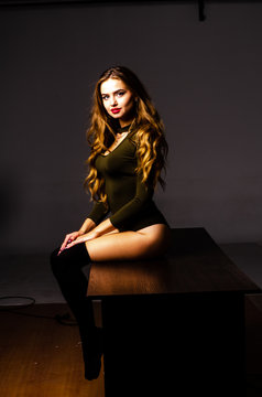 Beautiful dancer. Girl model. the girl sits in a hat and sits on a table. girl in a beautiful underwear. the girl is sitting on the table and fooling around, making faces. smooth, well-groomed legs