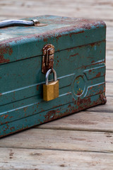 Rusty old toolbox locked up sitting on a wood