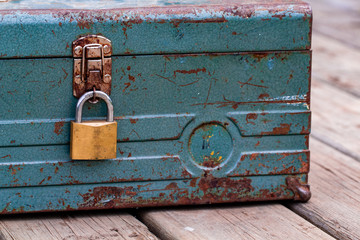 Rusty old toolbox locked up sitting on a wood
