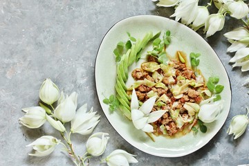 Yucca flowers dish. braised flower petals with minced meat and tomatoes. Served with avocado and pea sprouts as decoration. national cuisine of Costa Rica. edible flowers recipe.