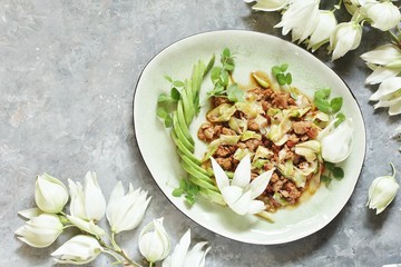 Yucca flowers dish. braised flower petals with minced meat and tomatoes. Served with avocado and pea sprouts as decoration. national cuisine of Costa Rica. edible flowers recipe.