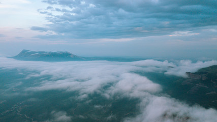 Fototapeta premium Misty sunrise over the valley and cliffs. Clouds over the mountains.