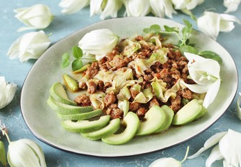 Yucca flowers dish. braised flower petals with minced meat and tomatoes. Served with avocado and pea sprouts as decoration. national cuisine of Costa Rica. edible flowers recipe.