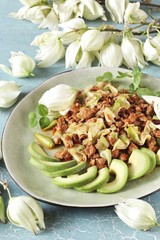 Yucca flowers dish. braised flower petals with minced meat and tomatoes. Served with avocado and pea sprouts as decoration. national cuisine of Costa Rica. edible flowers recipe.
