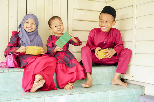 Three kids, happy siblings received money pocket or known as duit raya during Hari Raya Puasa or Eid Mubarak celebration. Muslim in Malaysian celebrate Eid with visiting other family and gathering