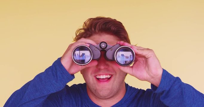 Young Funny, Surprised Man Using Binoculars To Search For Something And Finding It