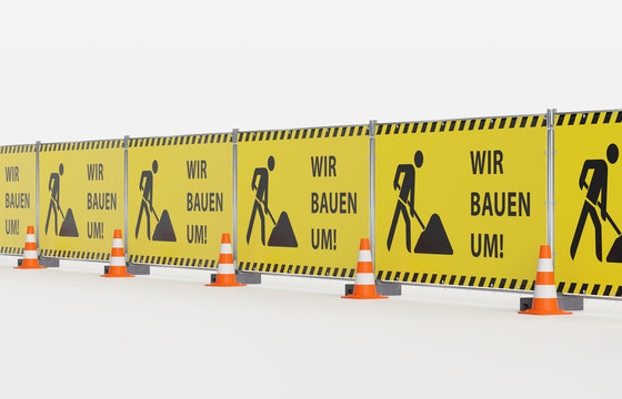 Baustelle Absicherung Mobilzaun Bauzaun - Mehrere Bauzaunfelder - schr&auml;g - mit Bauzaunbanner gelber Plane mit Warnmarkierung, Baustellensymbol und Text Wir bauen um - Pylone Leitkegel davor
