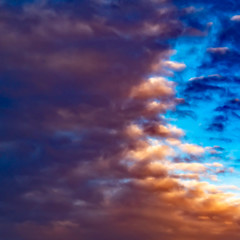 Square Defocussed view of a vast blue sky filled with puffy dark clouds at sunset