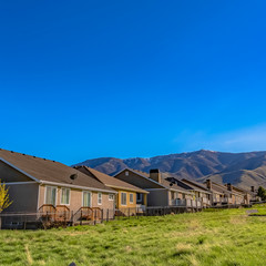 Square Houses on vast grassy field with a towering mountain in the distance