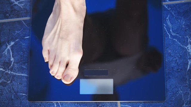 Person feet step on the weighing scale top view 4K