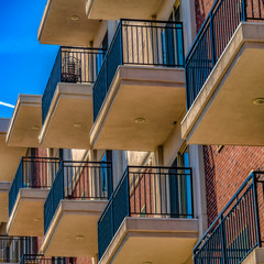Obraz premium Square Close up of building exterior with brick small balconies and red brick wall