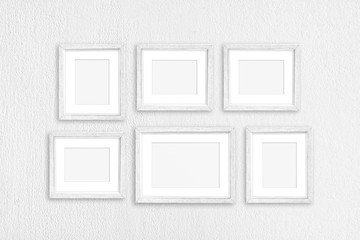 White frames collage, six old painted realistic frameworks isolated on white plastered wall, interior decor mock up