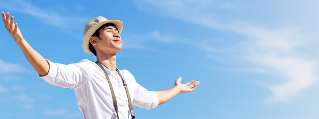 Candid of young attractive asian man close eyes, deep breath and wide open arms in blue sky view...