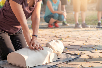Candid of mature asian female or older runner woman training on CPR demonstrating class in outdoor...