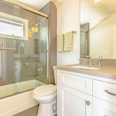 Square Bathtub and shower with glass door and window inside the bathroom of a home