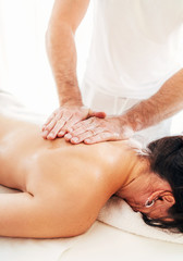 Obraz na płótnie Canvas Masseur man doing massage manipulations on the scapula area zone during massaging female body