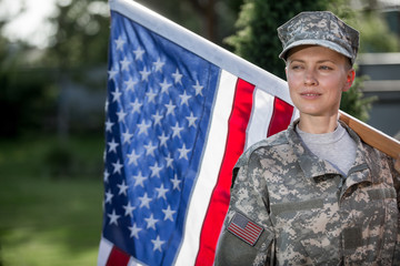 Beautiful american soldier in uniform standing in front of american flag