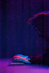 Hacker working with computer in dark room with digital interface around. Image with glitch effect.