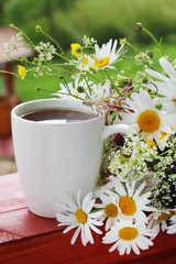 A cup of tea with daisies bouquet