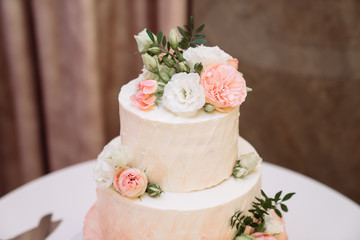 Big white wedding cake with pink roses on table