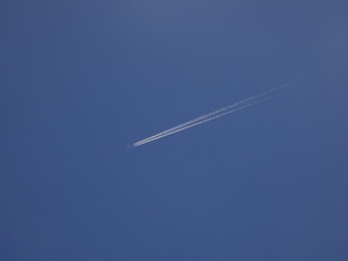 avión surcando el cielo azul y dejando una estela blanca