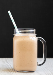 Banana apple smoothie in a glass jar mug, side view. Closeup.