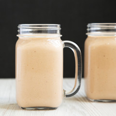 Banana apple smoothie in glass jars, side view. Close-up.