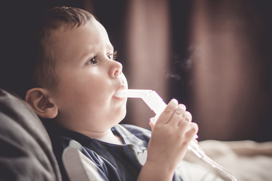 Two Year Old Boy Making Inhalation With Nebulizer At Home.